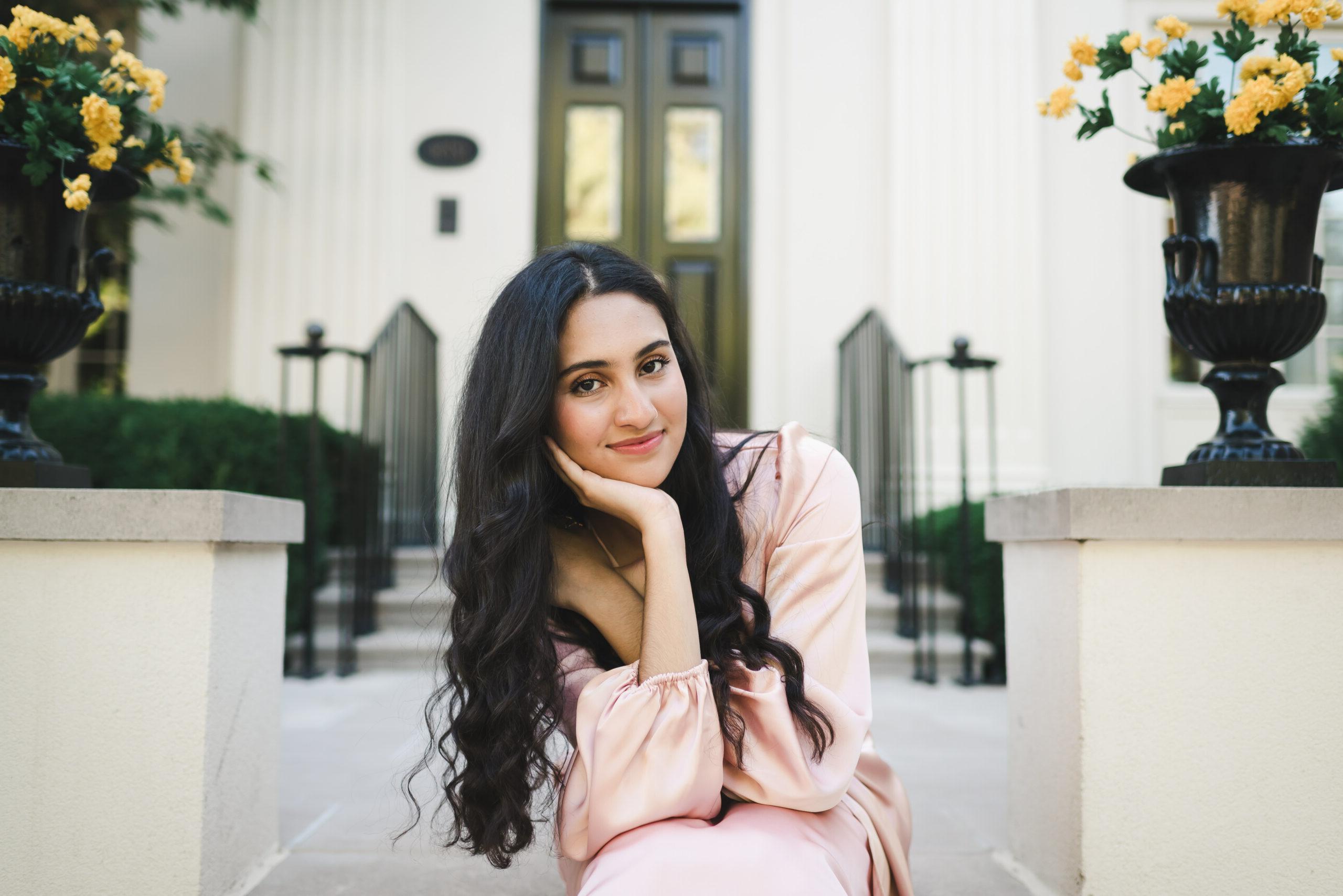 A female student sits on steps smiling